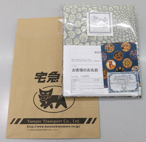 内袋に包まれたリバティプリント生地の商品と、宅急便用の外袋を並べた様子